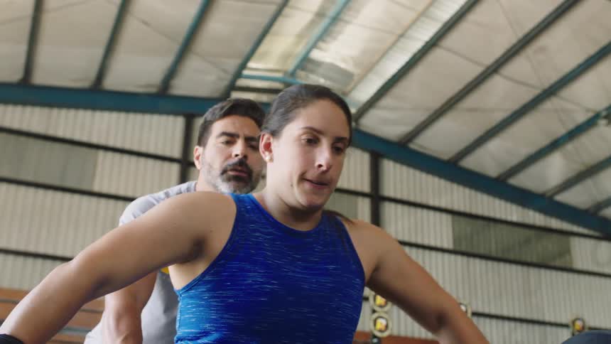 A woman deadlifts with a personal trainer