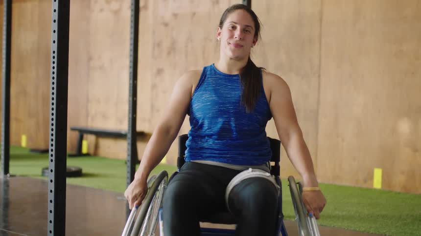 A woman in a wheelchair rolls forward and smiles