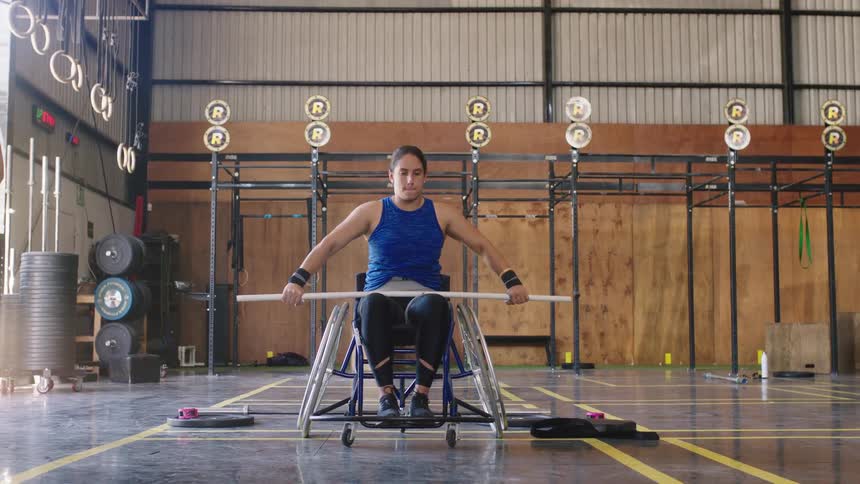 A woman is in a gym working out with a bar