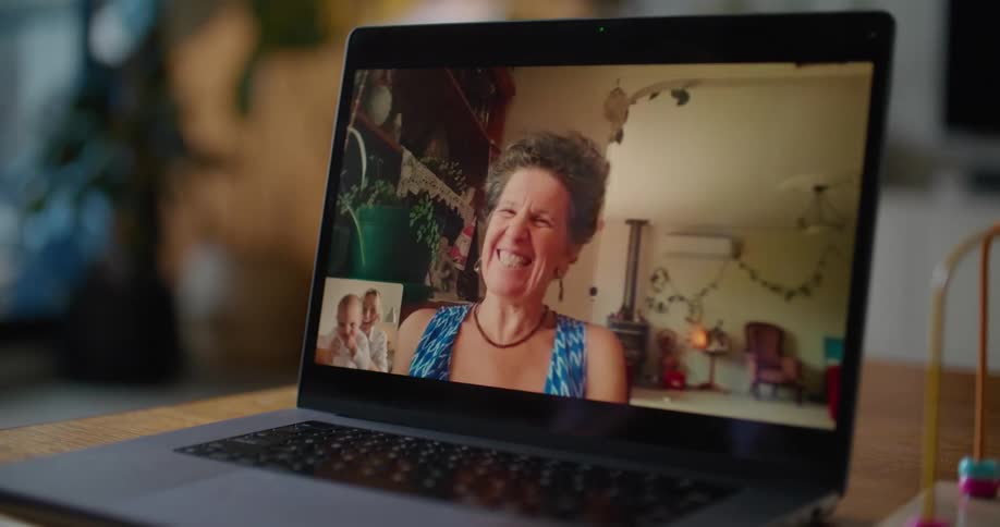 A woman holding a baby participates in a video chat with a smiling older woman