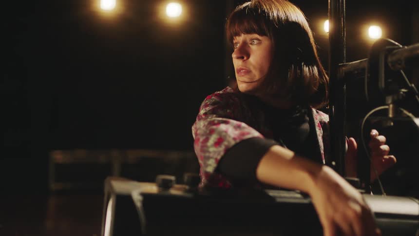 A woman is on stage with a video camera equipment