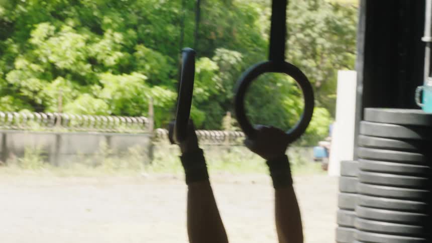 A woman exercising pulls herself up on rings