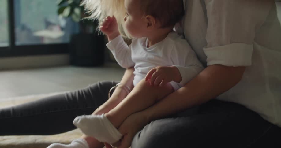 A woman sitting on the floor and putting socks on her babys feet