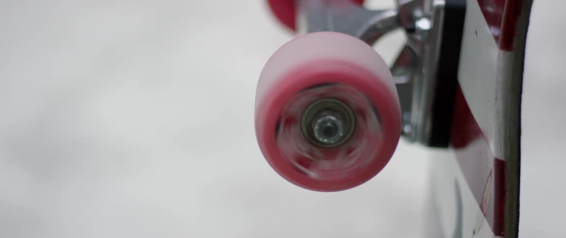 A red wheel on a skateboard is spinning