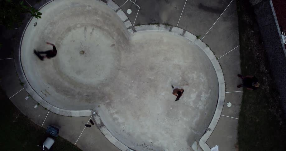 Men skateboard in an empty swimming pool