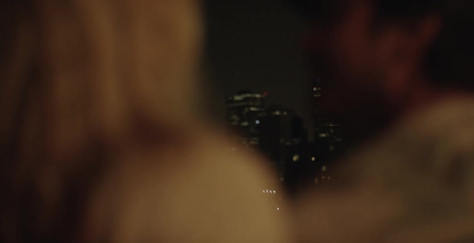 A couple kissing with a city skyline in the background
