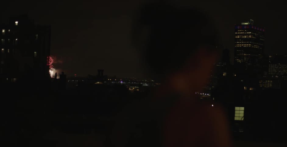 A woman watched the fireworks in the distance at night in the city