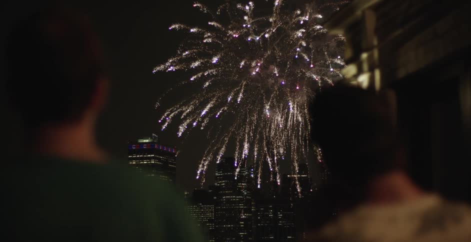 People watch the fireworks in the sky above the city