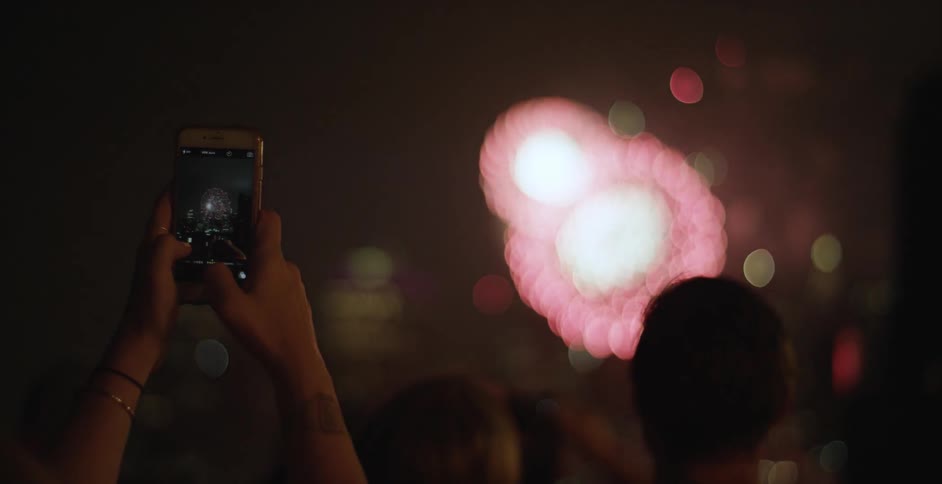 A woman recording fireworks on her phone