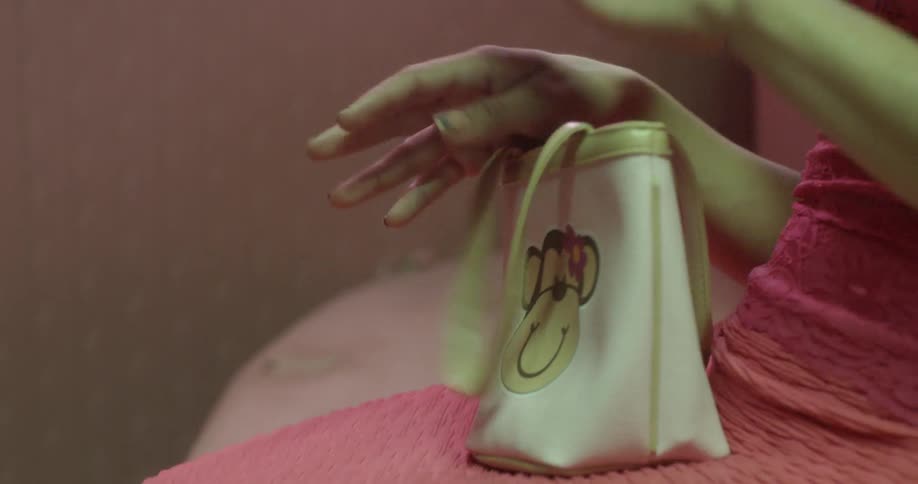 Close up of a woman inspecting her fingernails while holding a purse on her lap