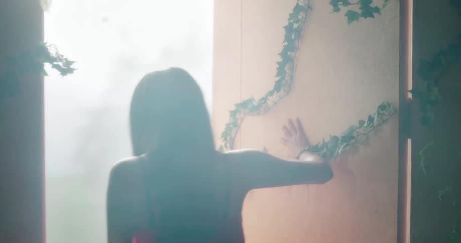 A woman pushing a door open and stepping out into the sunlight