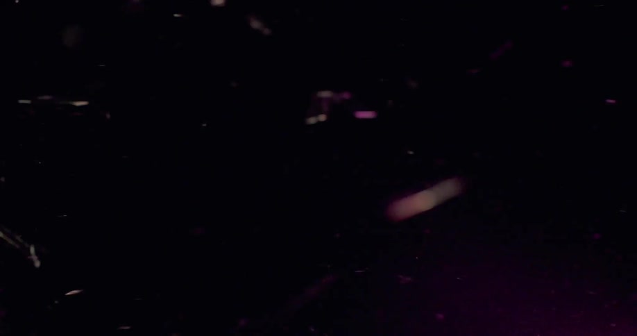 Broken glass flies through a dark area