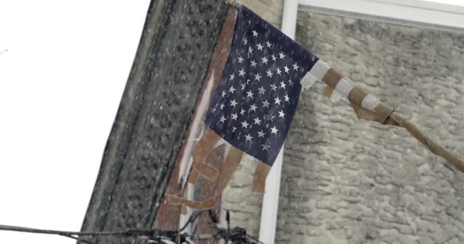 Snow falling around a tattered american flag