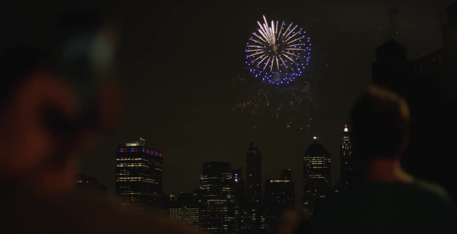 People are watching fireworks at night over a city