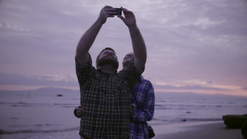 A man takes a picture with a woman near the water