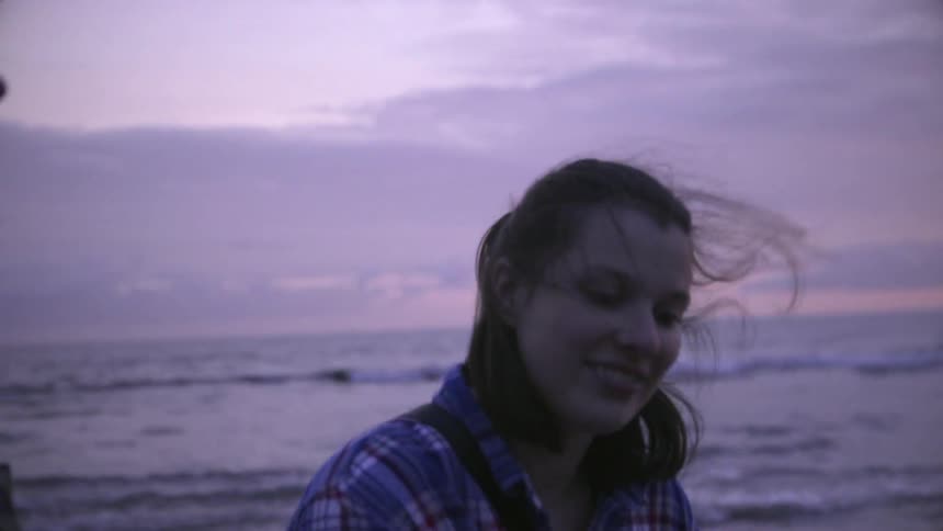 A woman picks up an orange object on the beach