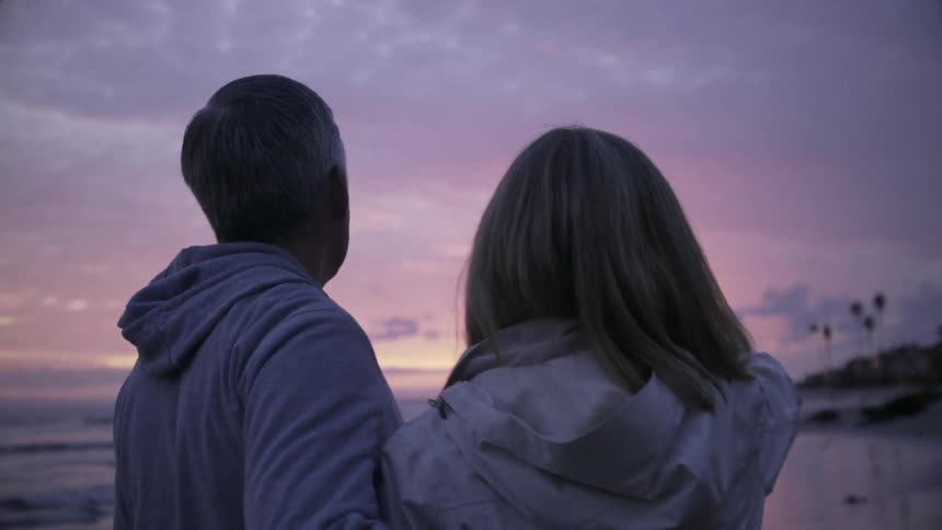 Man and woman embrace on the beach at sunset