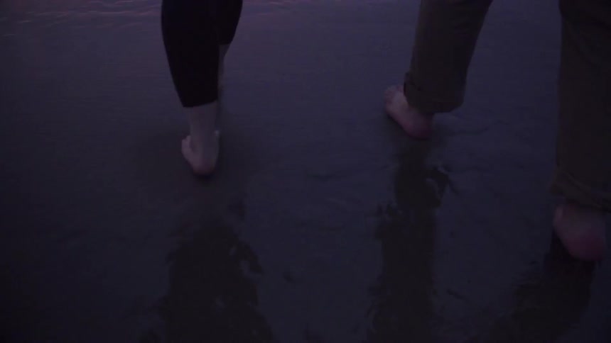 A couple walking along wet sand