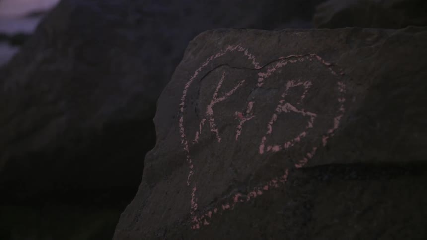 Initials written on a rock on a beach at sunset