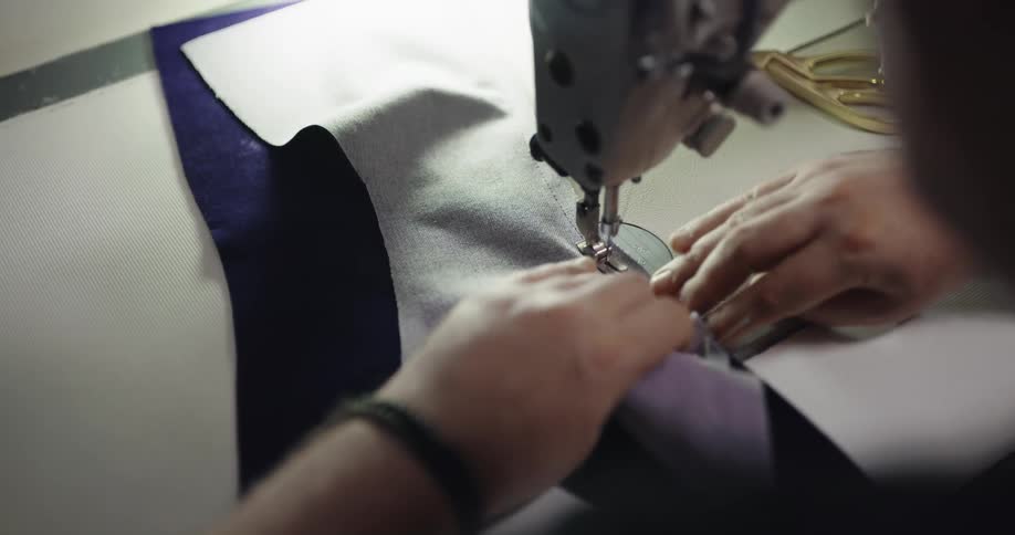 A person sews fabric with a sewing machine