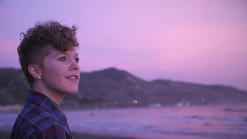 A short haired woman looks out at the ocean