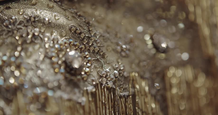 Close up of jewels and sequins sewn on a luxurious golden dress