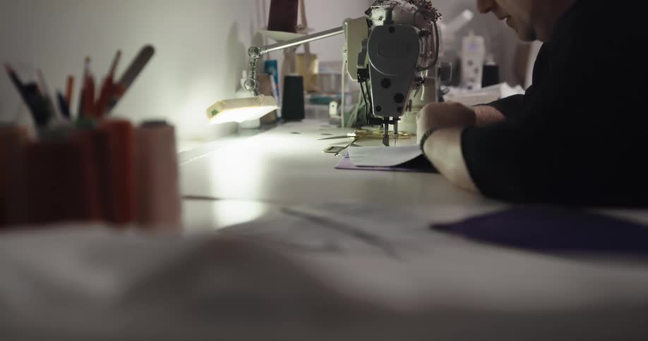 Fashion designer uses a sewing machine inside a workshop