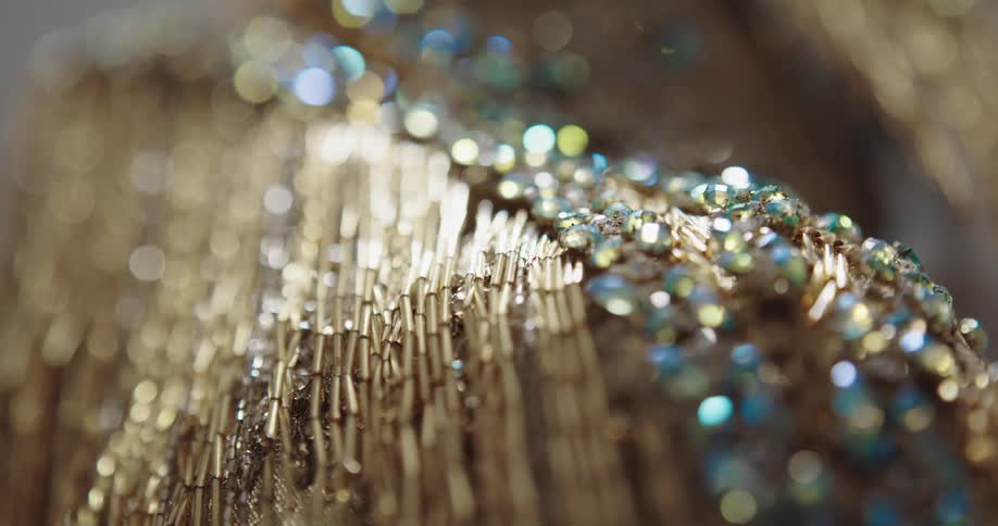 Close up of jewels and sequins sewn on a luxurious golden dress