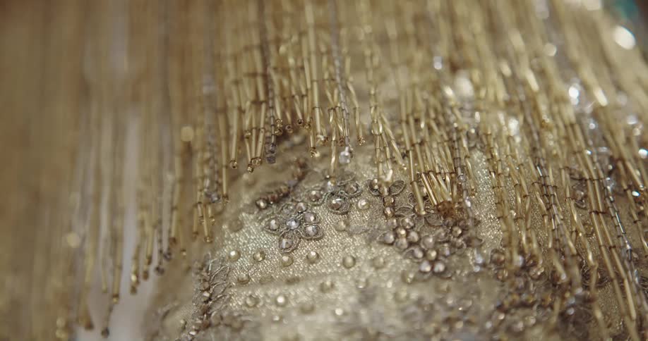 Close up of jewels and sequins sewn on a luxurious golden dress