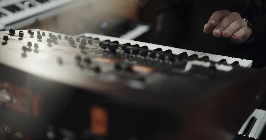 Musician playing the keyboard in front of a mixing dashboard control panel