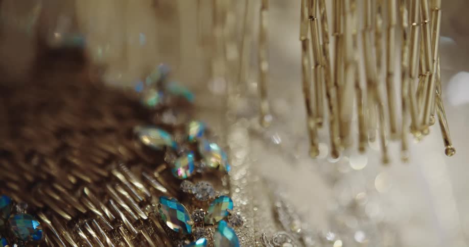Beaded strings hang over embroidered fabric