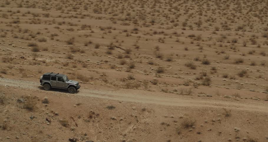 Car driving down a dirt path in a desert
