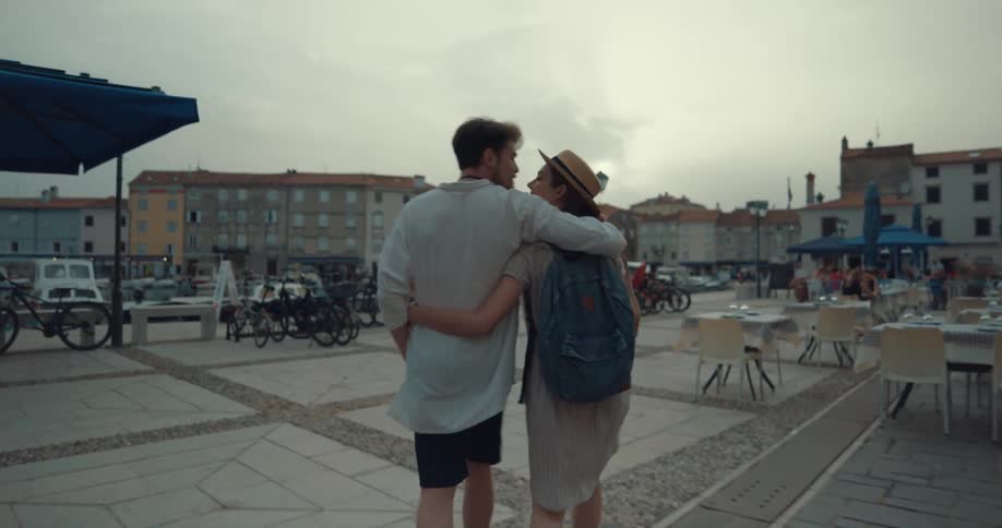 A couple walk through town and kiss