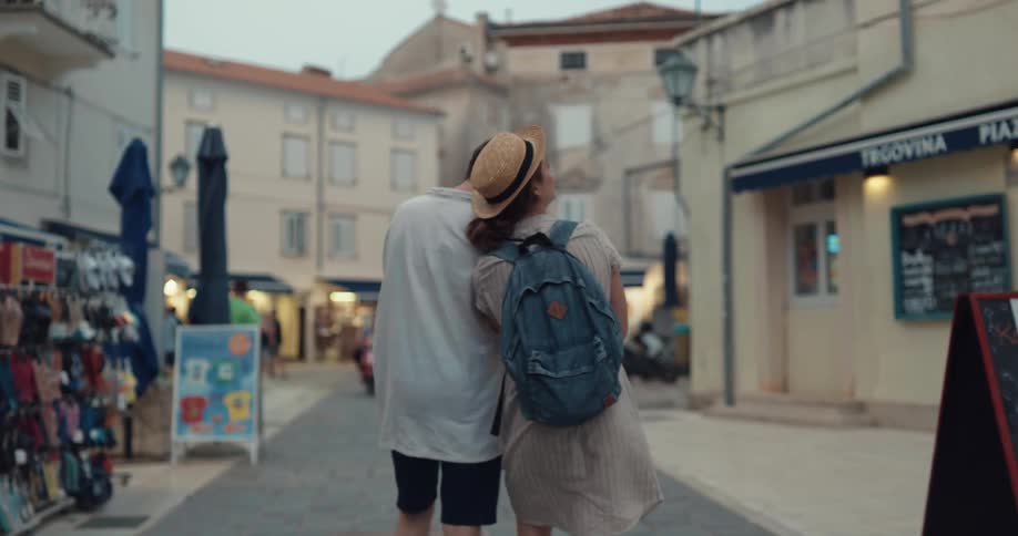 Tourist couple holding hands walking around the streets of an european city looking around in awe
