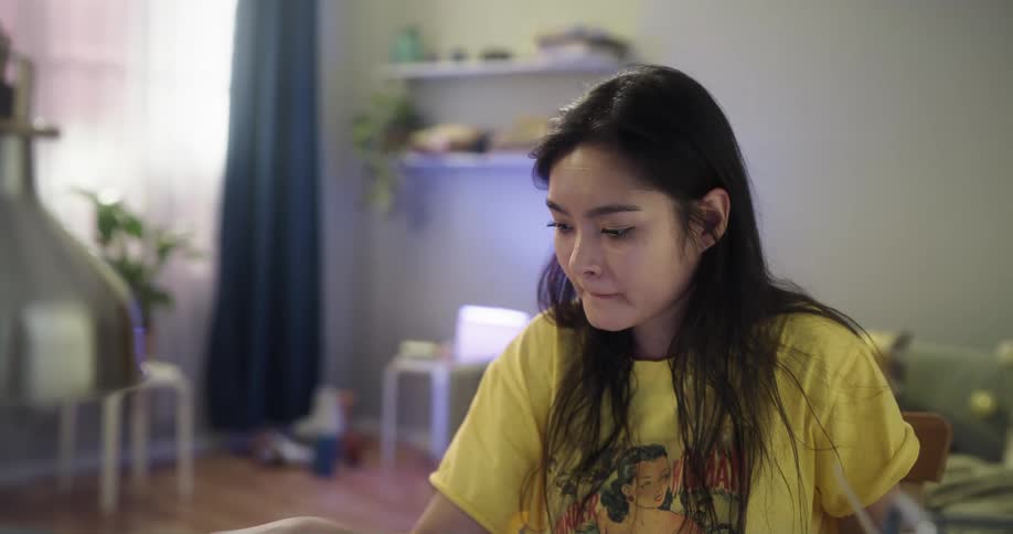 Woman looks at a monitor then reaches for a sheet of paper with a colorful design on it