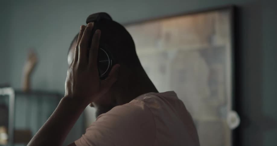 Man dances while listening to music in earphones on the living room at home