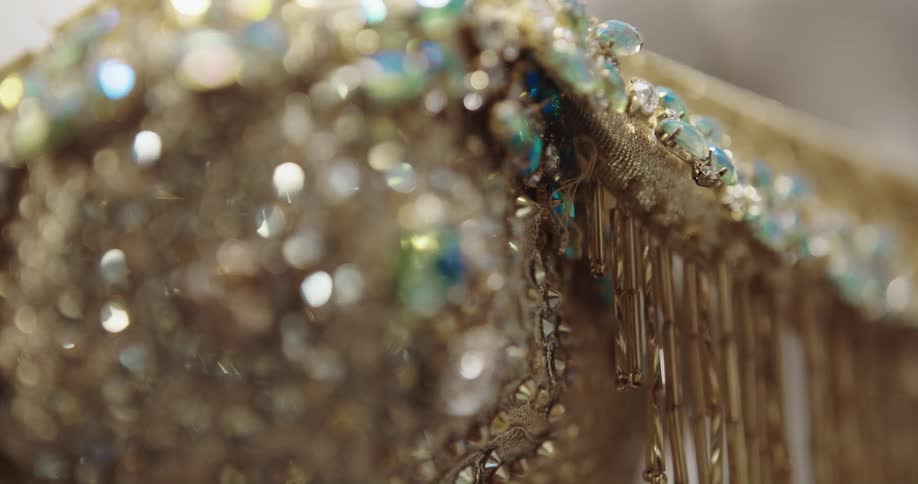 Close up of jewels and sequins sewn on a luxurious golden dress