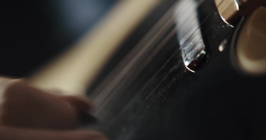 Close up of mans hands playing electric guitar with plectrum