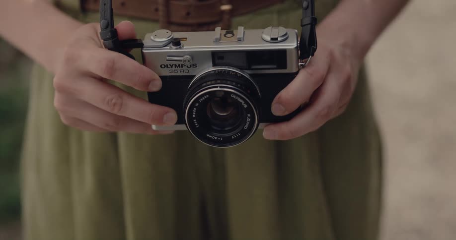 A woman wearing a camera around her neck lifts it up to take a picture