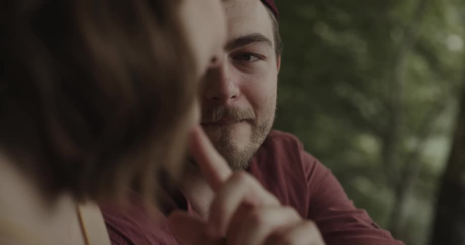 Man and woman are kissing outdoors in a wooded area