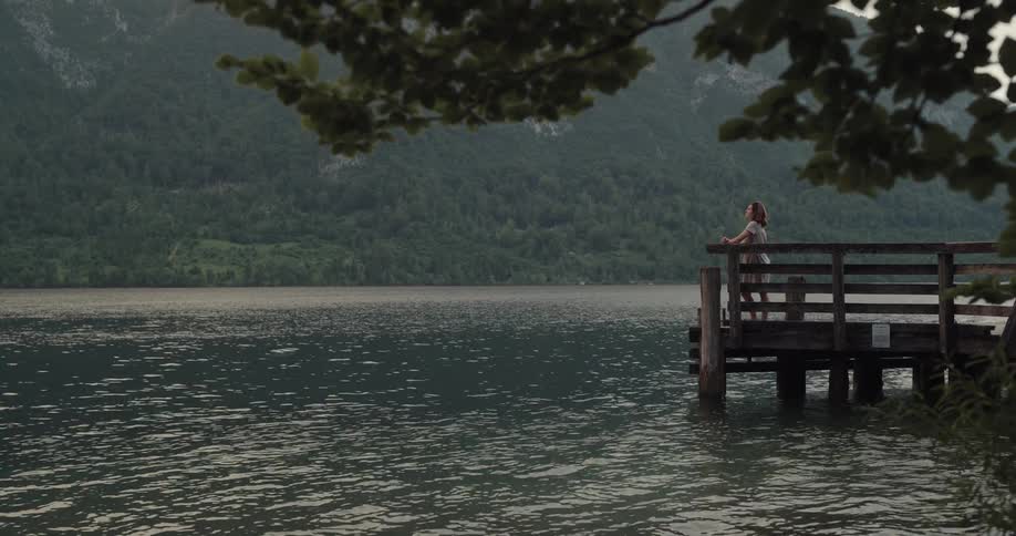 A woman standing on a pier overlooking a lake on a summer day