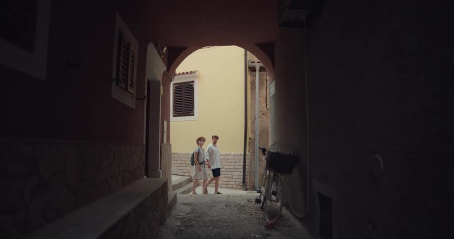 Alley of a small tourist town with a bike parked on the wall while a couple walks by in the background