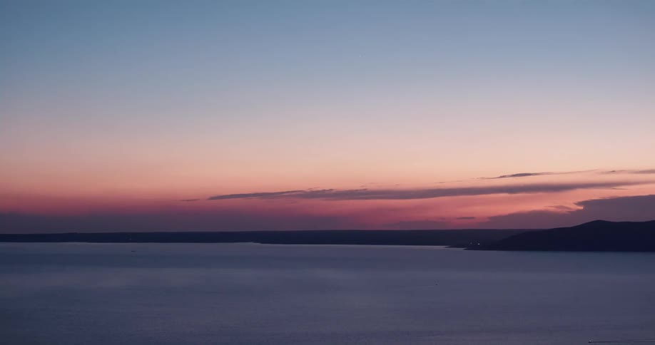 Red and blue sky at sunset over the ocean close to the mountains