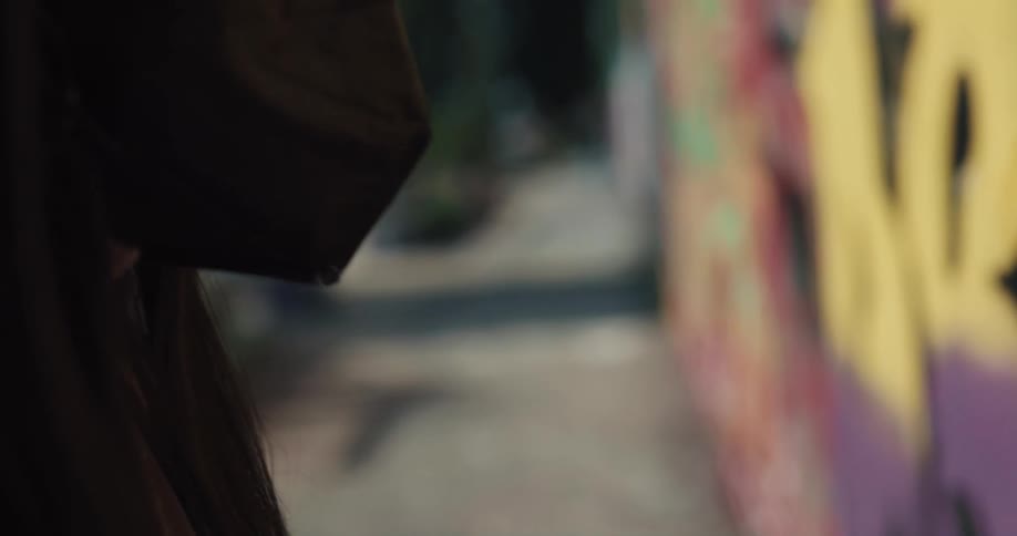 Black woman wearing a face mask doing graffiti in a graffiti wall at a public space during the day