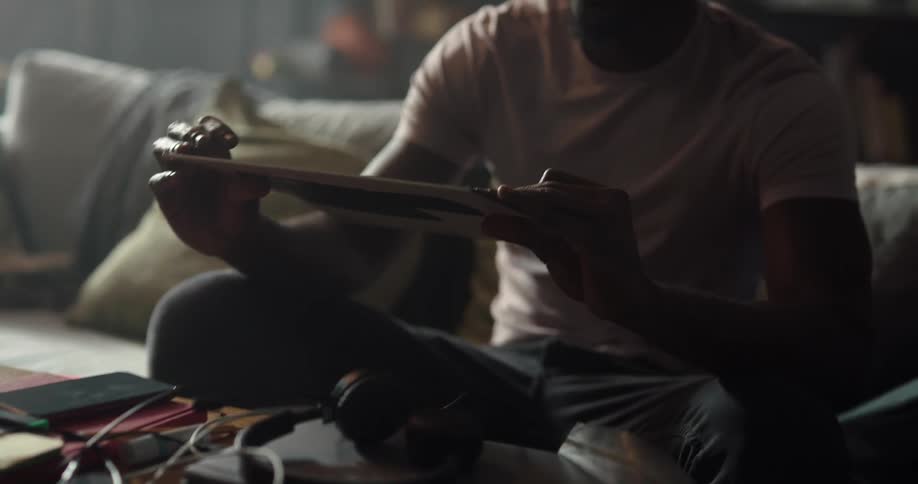 Man sitting on the couch happily looking at his vinyl record and getting up to put it on a record player