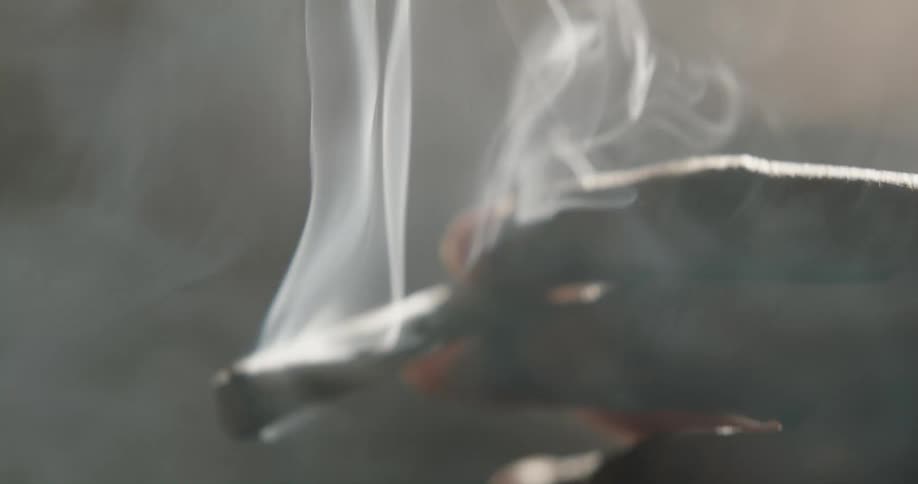 A man lights and smokes a cigarette while indoors
