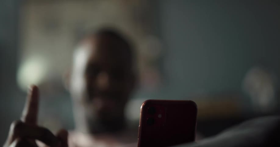 A black man is nodding his head and pointing his finger near his cell phone