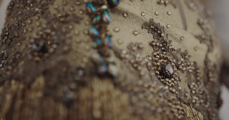 Close up of jewels and sequins sewn on a luxurious golden dress