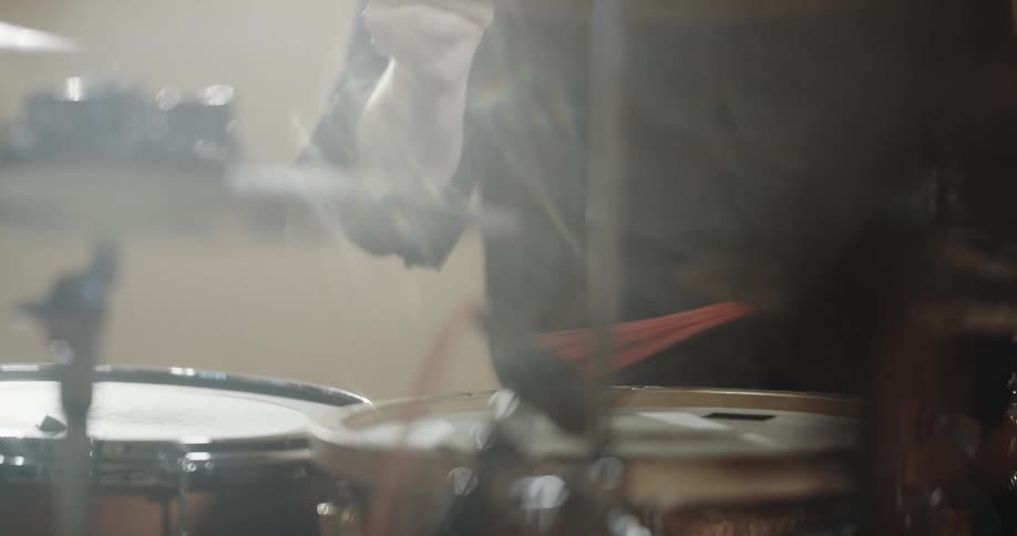 Close up of a mans arms as he plays the drums