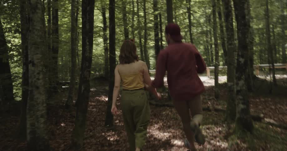 A woman is walking through the woods and a man runs after her and stops her trying to talk but she keeps going
